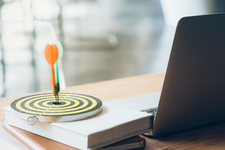 a target sitting on a book next to laptop with a dart in the center