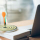 a target sitting on a book next to laptop with a dart in the center