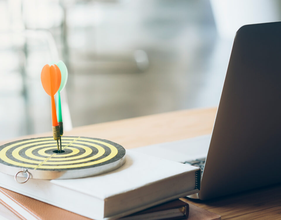 a target sitting on a book next to laptop with a dart in the center